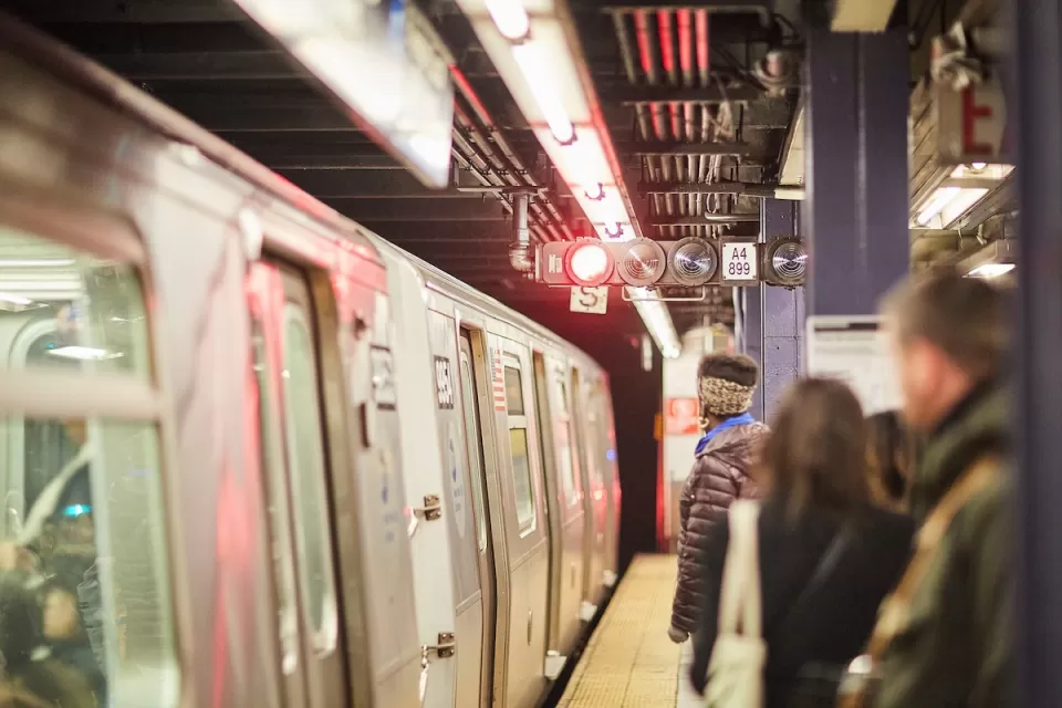 People waiting to board subway train on platform in New York City.
